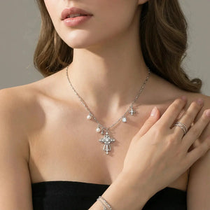 Woman wearing a silver cross pendant necklace with pearls and matching jewelry set