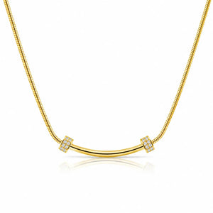 A gold necklace featuring a curved bar pendant flanked by two square bezel-set crystal clusters, suspended on a gold snake chain against a white background with a soft reflection.