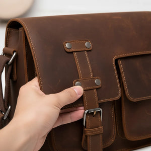 Men’s brown leather business messenger bag (first-layer cowhide) with adjustable shoulder strap, sized for a 12-inch laptop.
