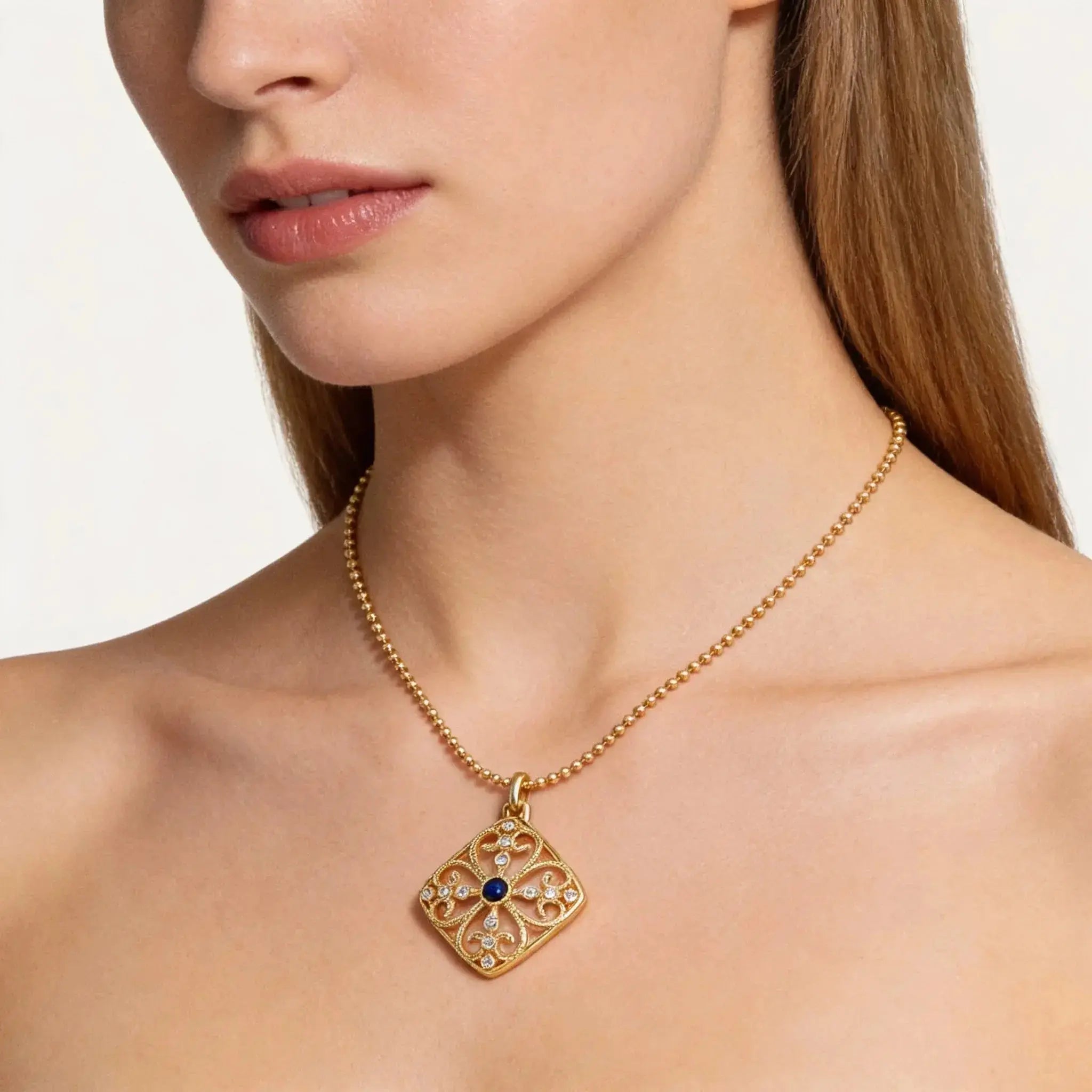 Woman wearing an 18K gold medallion necklace with lapis and diamond accents