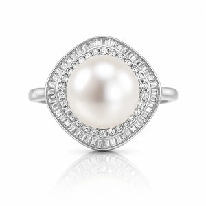 A silver ring featuring a large round white pearl surrounded by two halo rows of baguette-cut and round clear stones, shown on a white background with a soft reflection below.