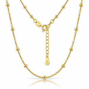 A gold beaded chain necklace with a matching extender chain and clasp, displayed on a clean white background with a subtle reflection.