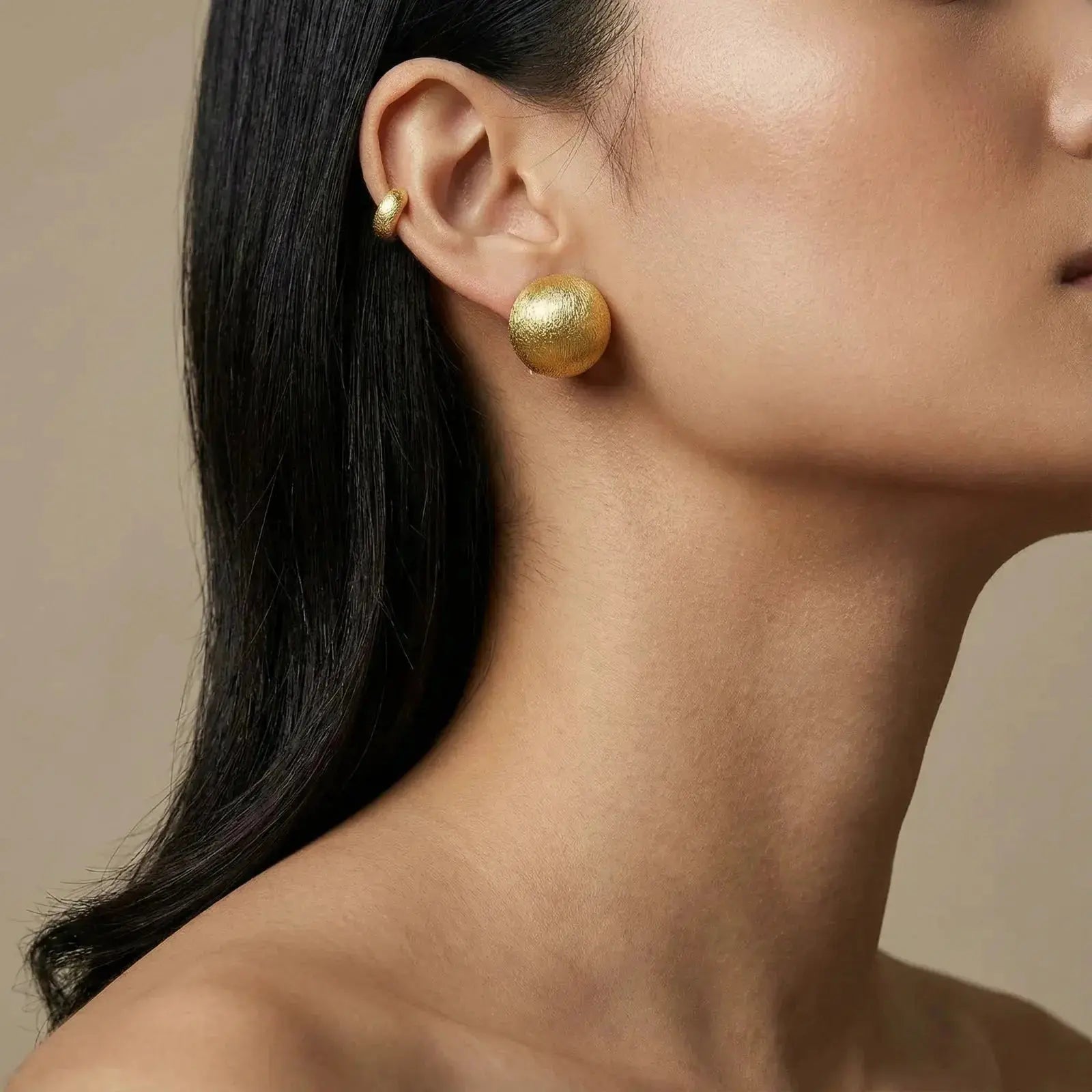 Woman wearing brushed 24K gold vermeil dome stud earrings, close-up on ear and jewelry