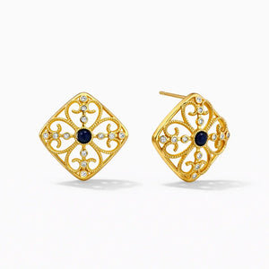 Gold stud earrings with intricate filigree, blue center stone, and clear gems on white background