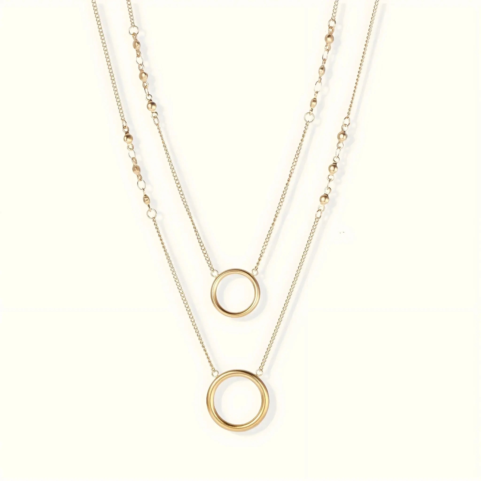 Two gold necklaces with circular pendants on a white background