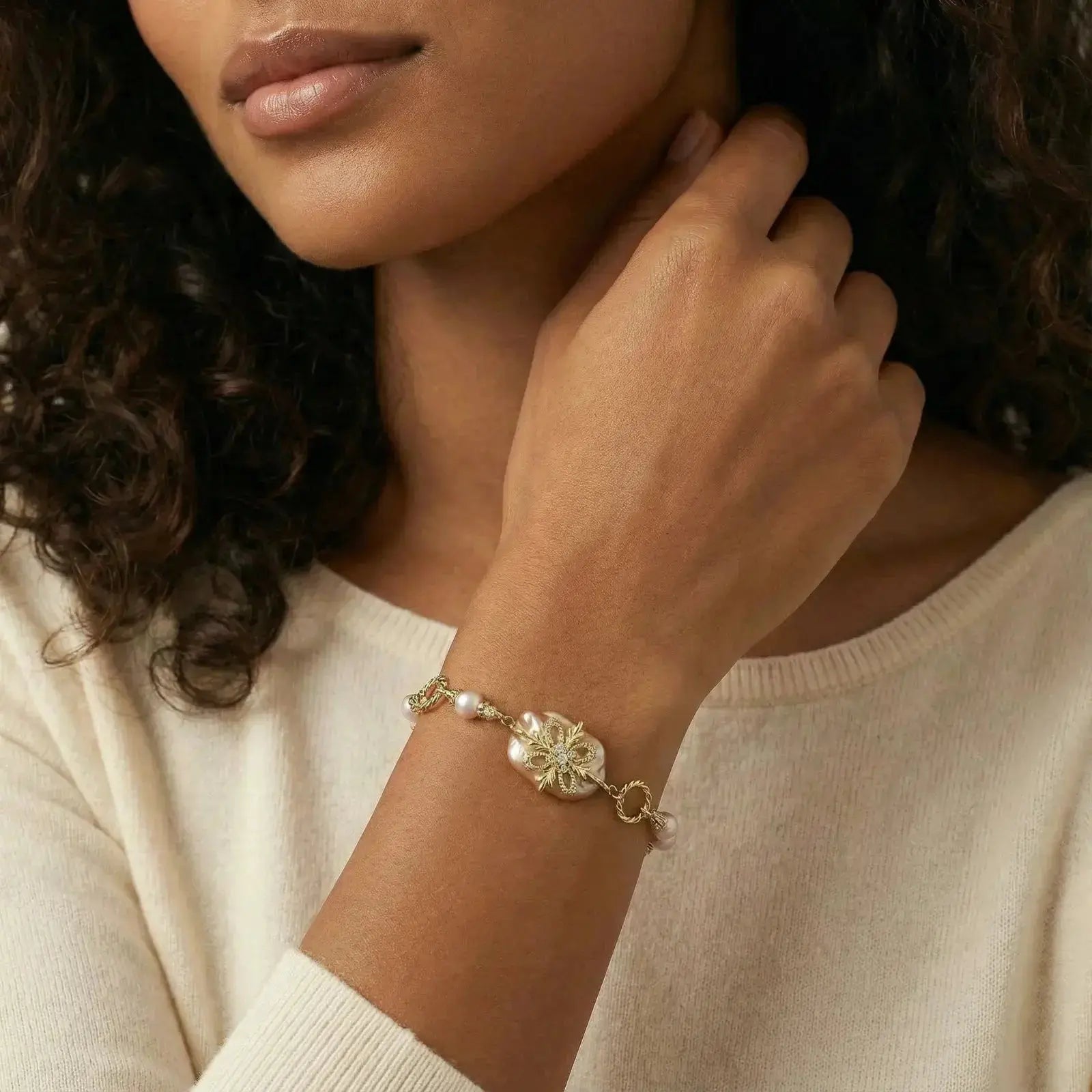Woman wearing a 14K gold baroque pearl flower bracelet on her wrist