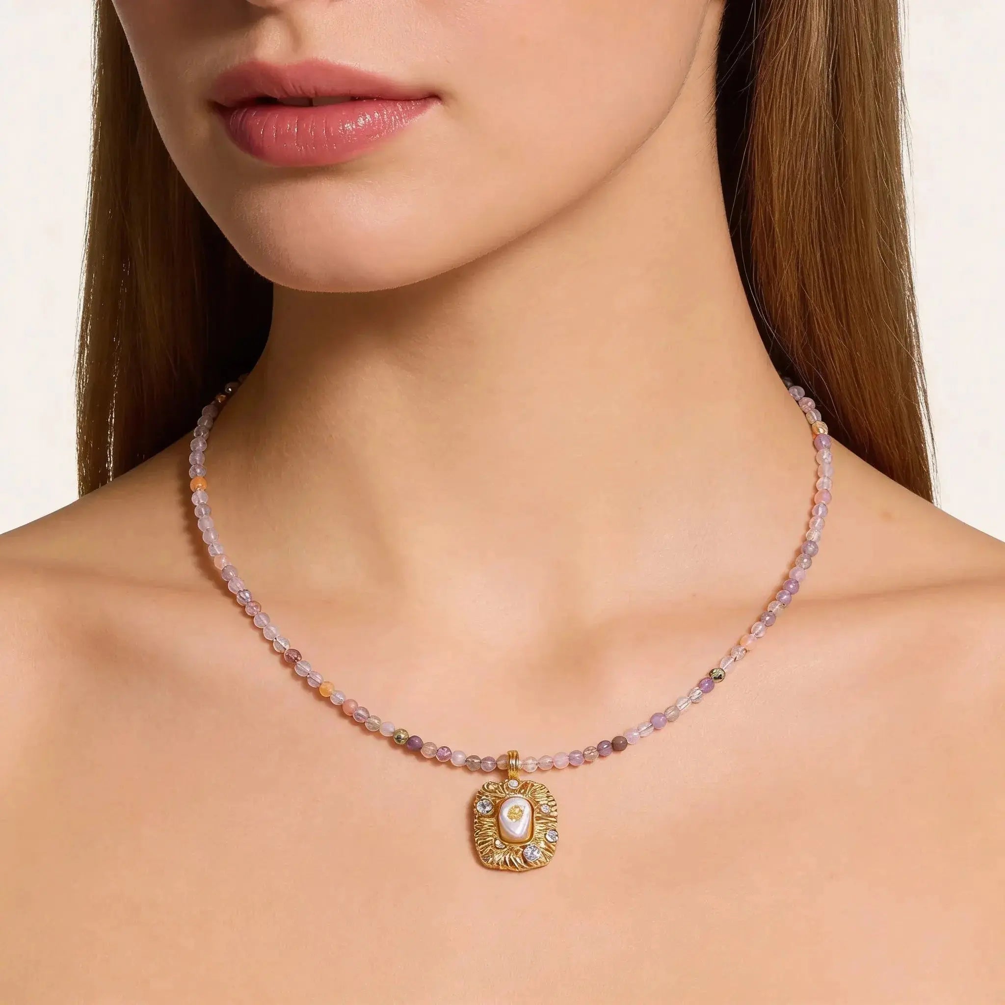 Woman wearing 18K gold gemstone pendant necklace with beaded chain and decorative charm