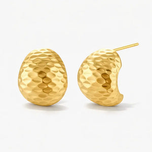 Gold hammered huggie earrings with textured surface on a plain white background