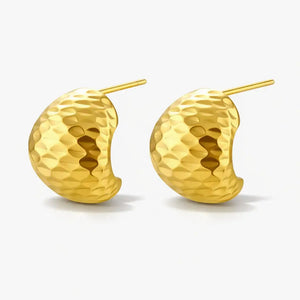 Gold hammered huggie earrings with textured finish on white background