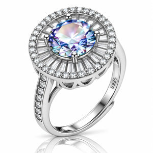 A silver halo ring featuring a large round iridescent blue-purple center stone surrounded by a halo of small clear stones, with a shank paved with tiny clear stones. The ring is marked 925 sterling silver and shown on a clean white background with a soft reflection below.