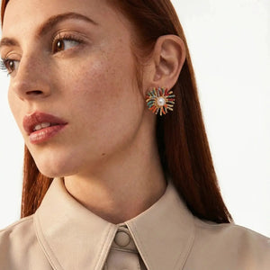 Close-up of a woman wearing colorful earrings with a neutral background