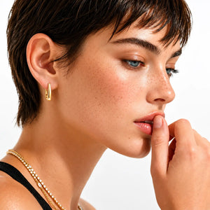 Close-up of a woman's face with gold earring and necklace on a white background