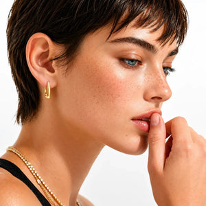 Close-up of a woman's face with gold earring and necklace on a white background