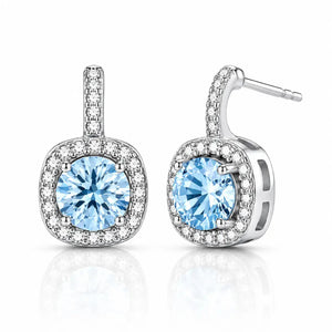 A pair of silver-toned drop earrings featuring a large round-cut light blue gemstone in a halo setting, with smaller clear stones along the top bar and around the square-shaped drop, shown on a white background with a soft reflection.