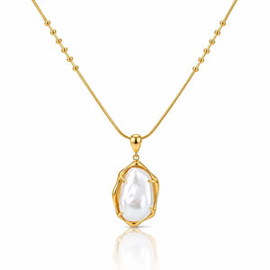 A gold necklace with a beaded chain and a bezel-set irregular baroque pearl pendant, shown on a clean white background with a soft reflection below.