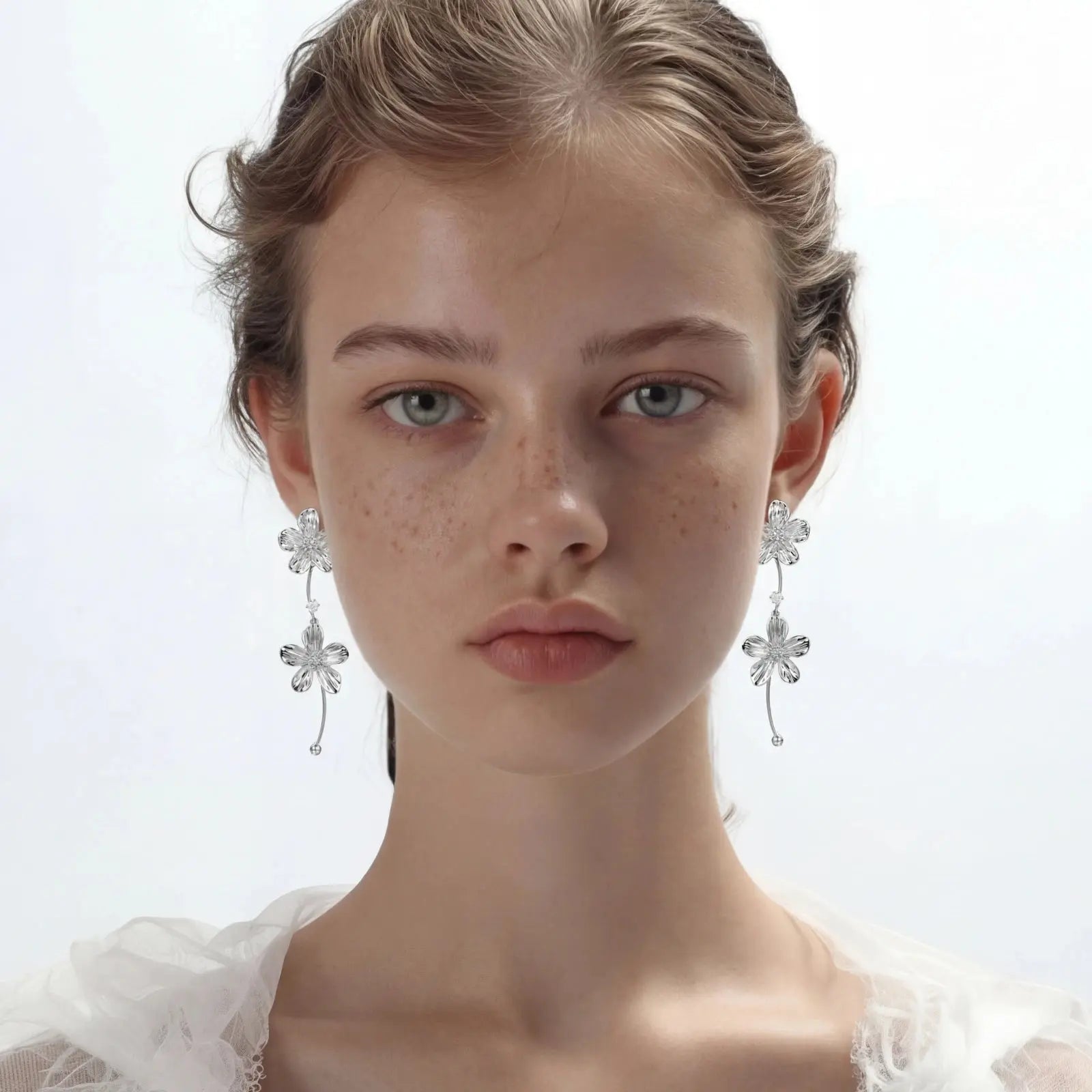 Model wearing silver floral cascade dangle earrings with delicate flower design
