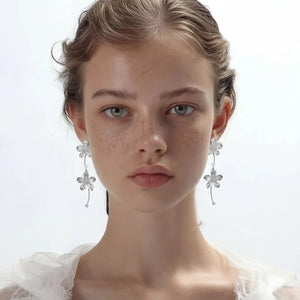 Model wearing silver floral cascade dangle earrings with delicate flower design