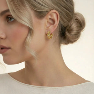 Close-up of a woman wearing gold earrings with a neutral background