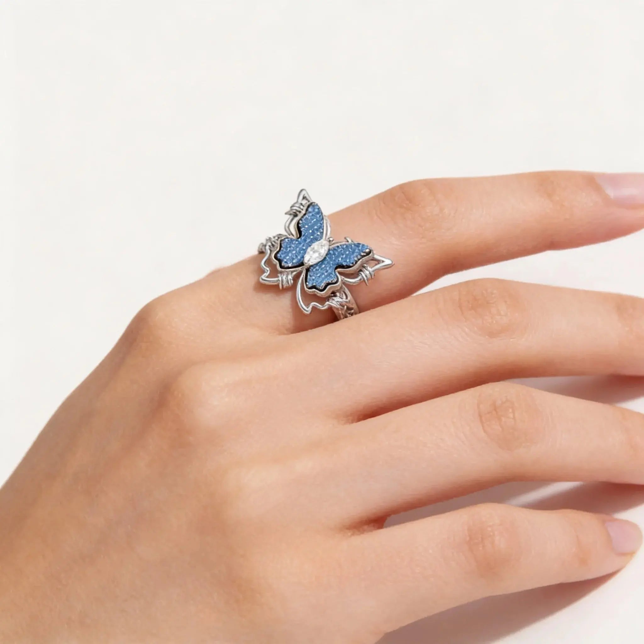 Butterfly-shaped ring on a person's finger against a white background