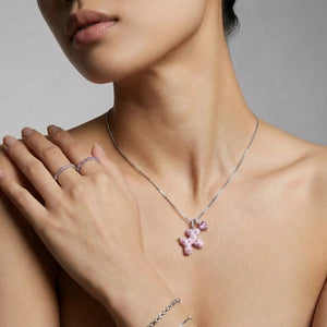 Woman wearing a pink teddy bear charm necklace with matching rings and bracelets