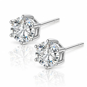 A pair of round-cut diamond stud earrings in a polished silver-tone setting, displayed on a clean white background with soft reflections below.