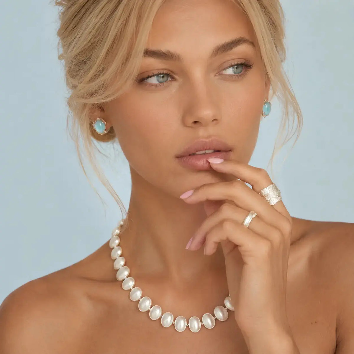 Woman wearing a pearl necklace with a light blue background