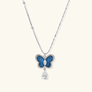 Butterfly necklace with blue gem and teardrop pendant on a white background