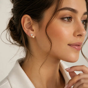 A close-up of a woman wearing a small gold star-shaped stud earring, shown from the side against a soft light background.