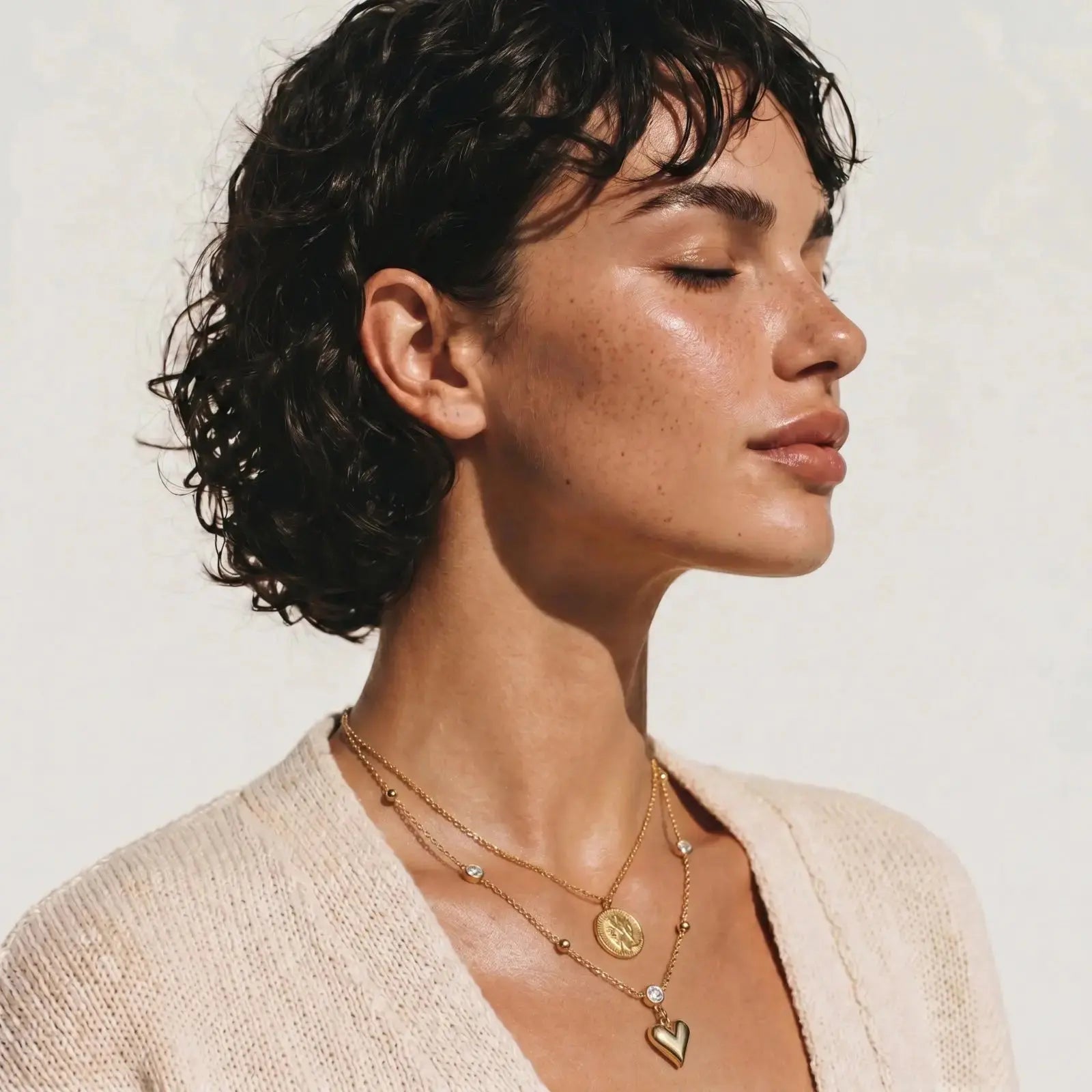 Woman wearing gold necklaces with a neutral background