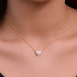 Gold necklace with a heart-shaped diamond pendant on a person's neck.