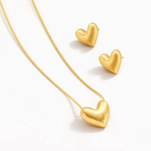 Gold heart-shaped necklace and earrings on a white background
