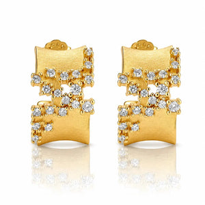 A pair of gold geometric stud earrings with clear gemstones, displayed on a clean white background with a soft reflection below.