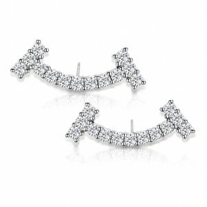 A pair of silver-toned crescent-shaped stud earrings set with clear pavé gemstones, displayed on a clean white background with a soft reflection.