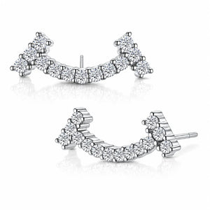 A pair of silver-toned crescent-shaped stud earrings set with multiple round clear gemstones, displayed on a clean white background with soft reflections.