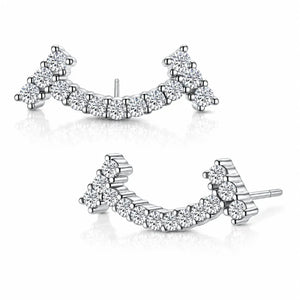 A pair of silver-toned crescent-shaped stud earrings set with multiple round clear gemstones, displayed on a clean white background with soft reflections.