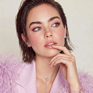 Woman wearing a necklace and earrings with a soft pink background