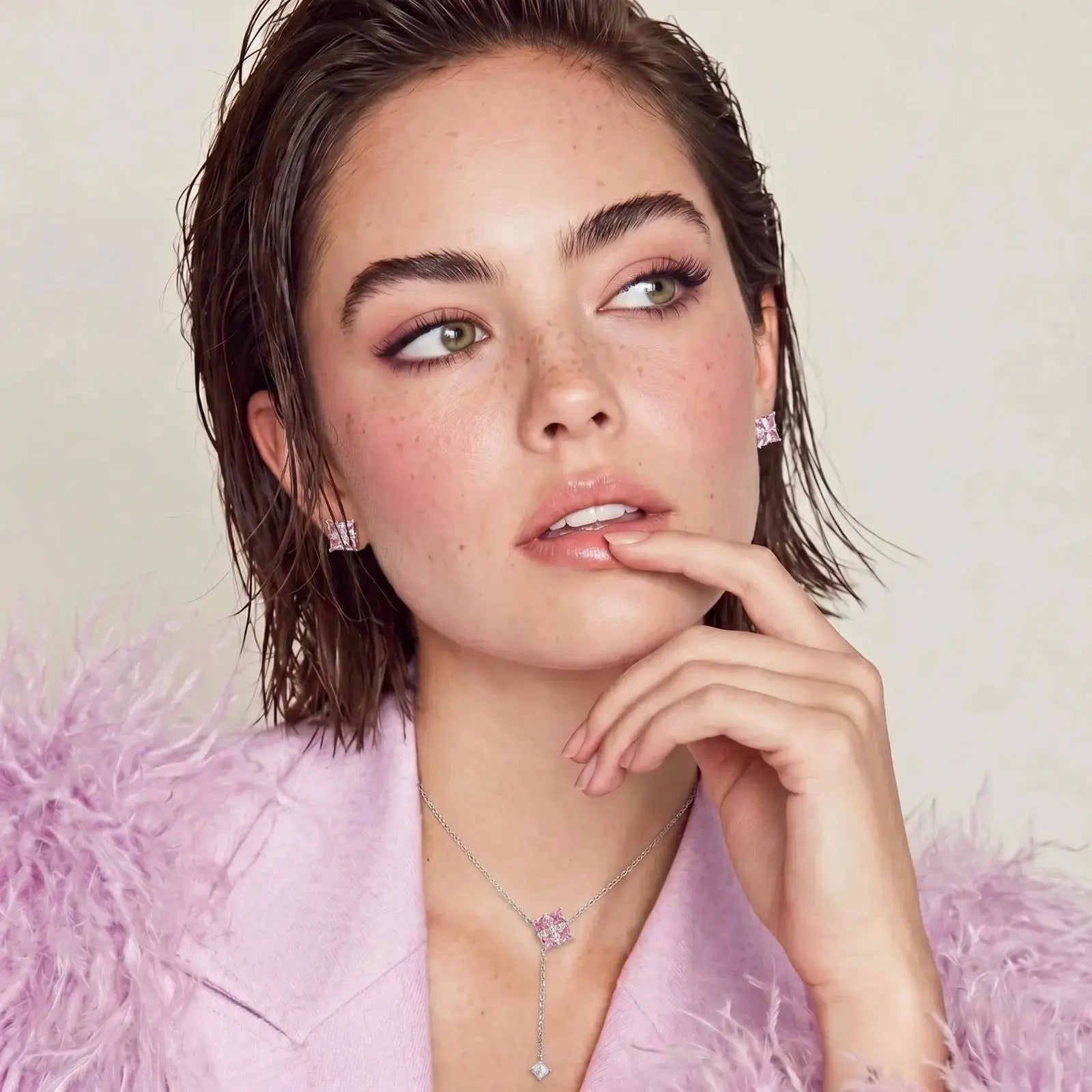 Woman wearing a necklace and earrings with a soft pink background