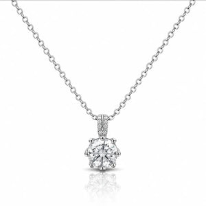A silver solitaire necklace with a round-cut diamond pendant and a pavé diamond bail, displayed on a clean white background with a soft reflection below.