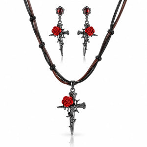 A gothic-style jewelry set featuring a multi-strand black cord necklace with a dagger cross pendant adorned with a red rose, accompanied by matching drop earrings, shown on a clean white background.