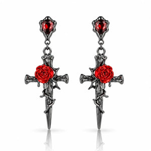 A pair of gothic dangle earrings featuring dark silver-toned metal crosses with red rose details and red gemstone accents, shown on a clean white background with subtle reflections.