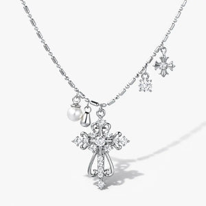 Layered silver necklace with crystal cross and pearl charms on a white background