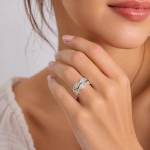 A close-up lifestyle shot of a woman's hand wearing a silver-toned diamond ring with an intricate openwork pattern.