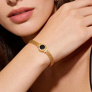 Gold bracelet with a black stone on a wrist, close-up shot.