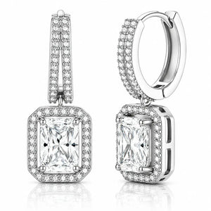A pair of silver-toned huggie hoop earrings with rectangular princess-cut diamond drops, surrounded by halo and channel settings of small round diamonds, shown on a white background with a subtle reflection.