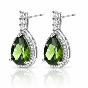 A pair of silver-tone drop earrings featuring large faceted green teardrop gemstones surrounded by small clear stones, with a three-stone cluster at the top, shown on a white background with a soft reflection below.
