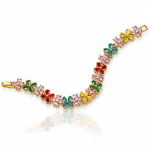 A gold-plated bracelet featuring a series of colorful flower motifs in red, green, blue, and yellow, each embellished with small pink stones, displayed on a clean white background with a soft reflection.