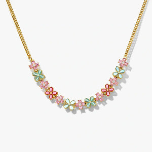 Gold chain necklace with pink, blue, and red floral charms and crystals on white background