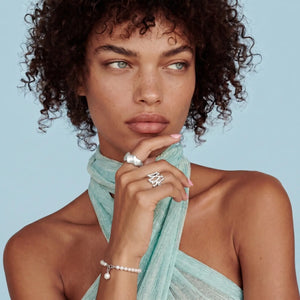 Woman wearing a light blue scarf with jewelry against a light blue background