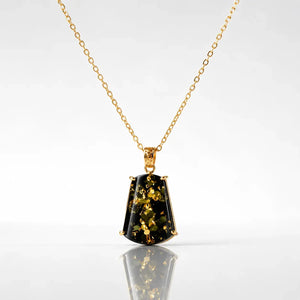 Gold necklace with a pendant featuring green gemstone on a white background