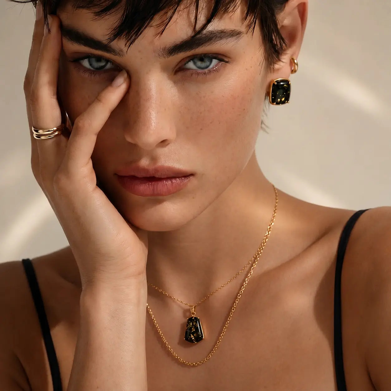 Close-up of a woman wearing gold jewelry with a neutral background